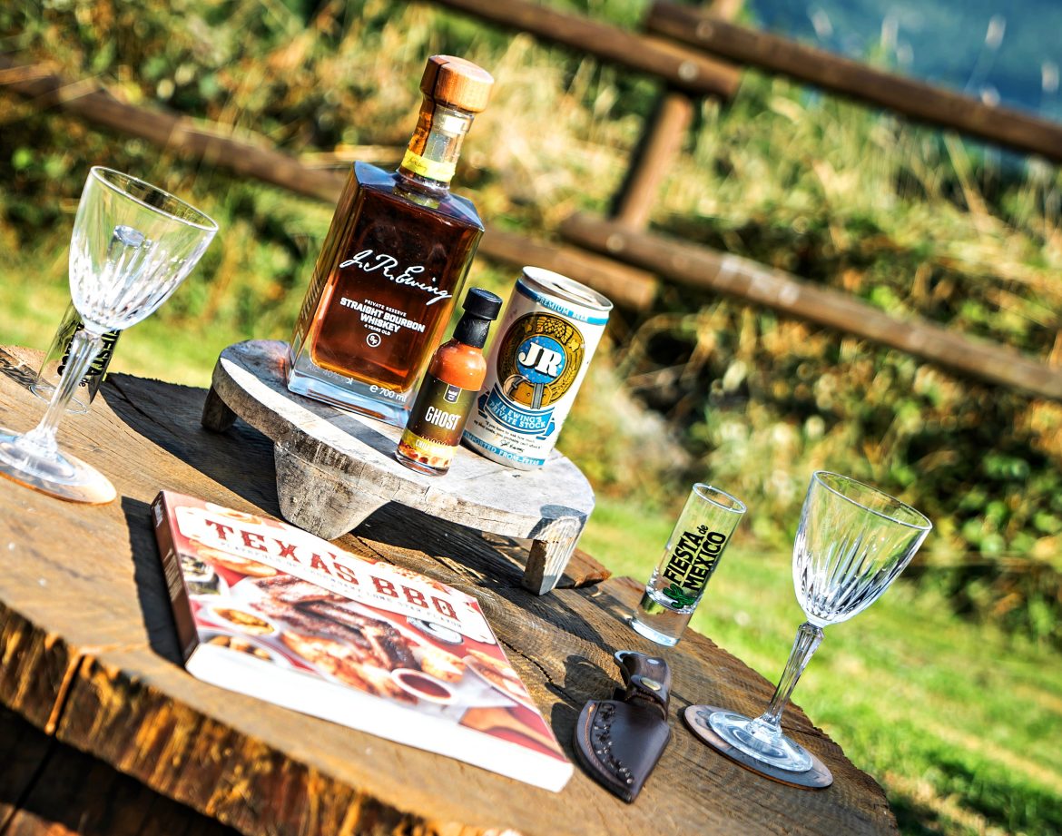 Détente en pleine nature avec un bar en bois, verre à whisky et livre de recettes BBQ.