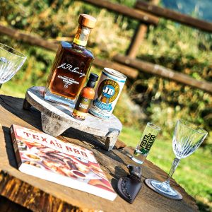Détente en pleine nature avec un bar en bois, verre à whisky et livre de recettes BBQ.