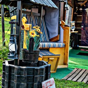 Hébergement insolite : un charmant puits décoratif avec des fleurs, près d'une cabane accueillante.