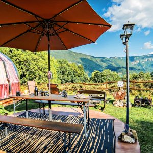 Hébergement insolite : une yourte colorée avec terrasse, vue imprenable sur les montagnes.