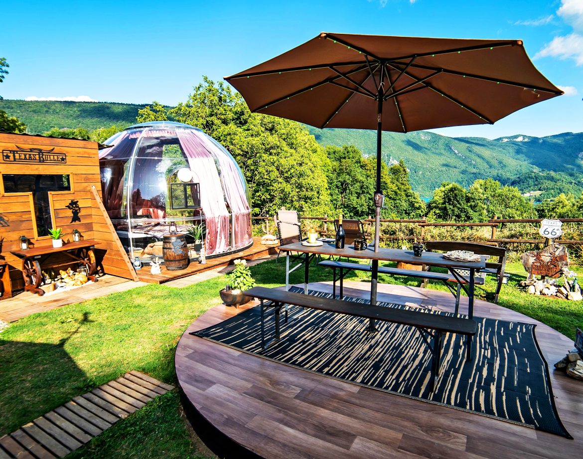 Hébergement insolite : bulle transparente avec terrasse en bois, vue imprenable sur la nature.