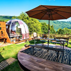 Hébergement insolite : bulle transparente avec terrasse en bois, vue imprenable sur la nature.