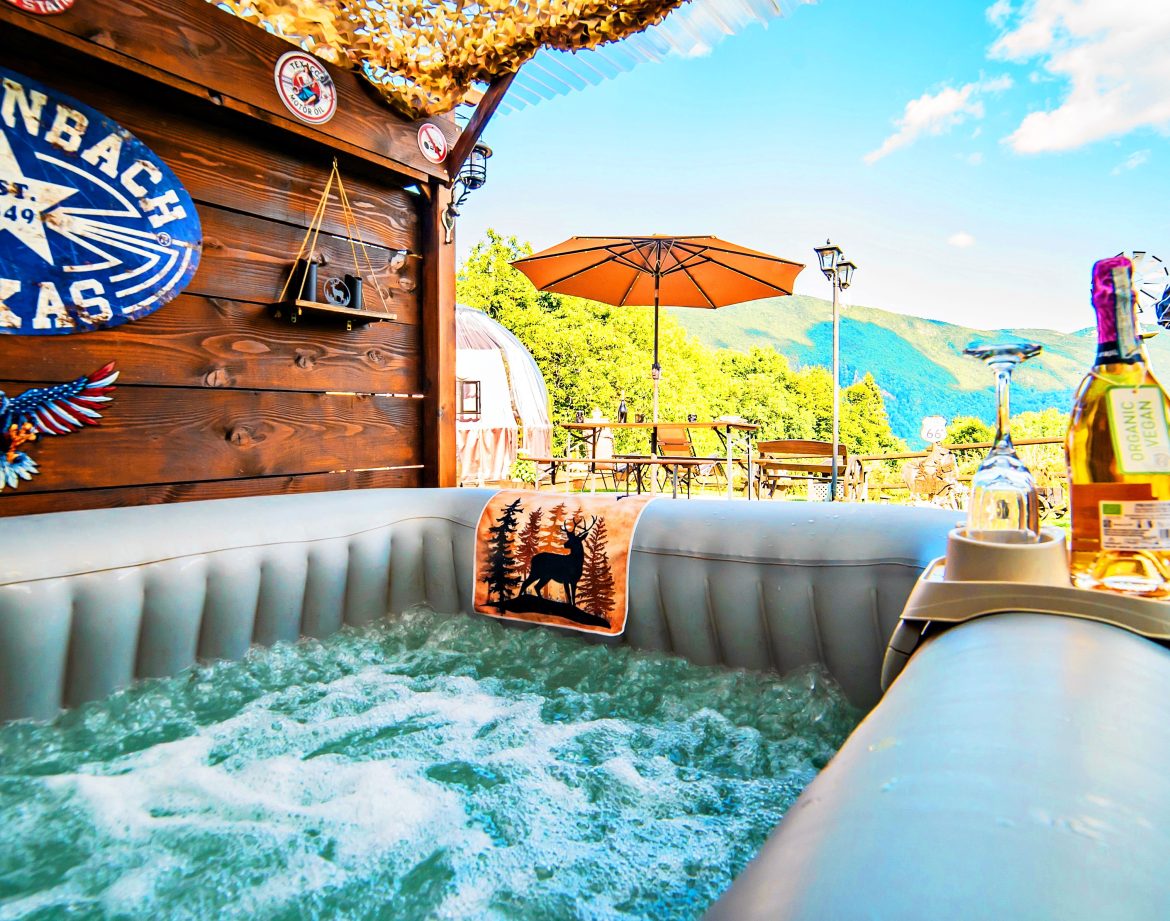 Bain à remous dans un hébergement insolite, avec vue sur les montagnes et parasol.