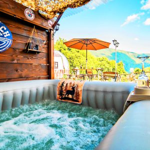 Bain à remous dans un hébergement insolite, avec vue sur les montagnes et parasol.