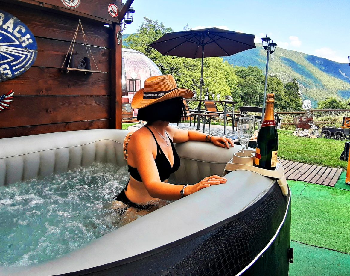 Bain à remous en plein air avec vue sur les montagnes, ambiance relaxante et estivale.
