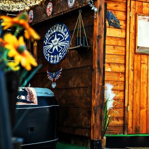 Cabane en bois chaleureuse avec décorations artisanales et fleurs colorées en avant-plan.