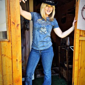 Cabane en bois avec une hôtesse en cowboy, chapeau noir et pistolet en plastique à la main.