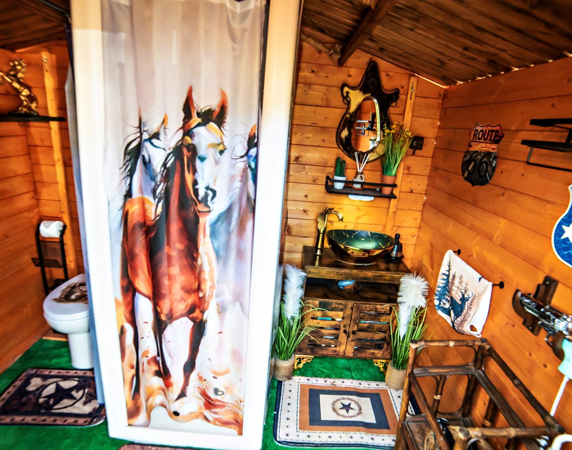 Cabane en bois avec décoration équestre, incluant une douche originale et des accessoires rustiques.