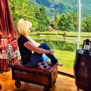 Hébergement insolite : bulle transparente avec vue panoramique sur les montagnes verdoyantes.