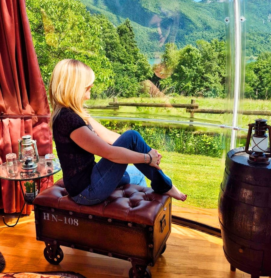 Hébergement insolite : bulle transparente avec vue panoramique sur les montagnes verdoyantes.