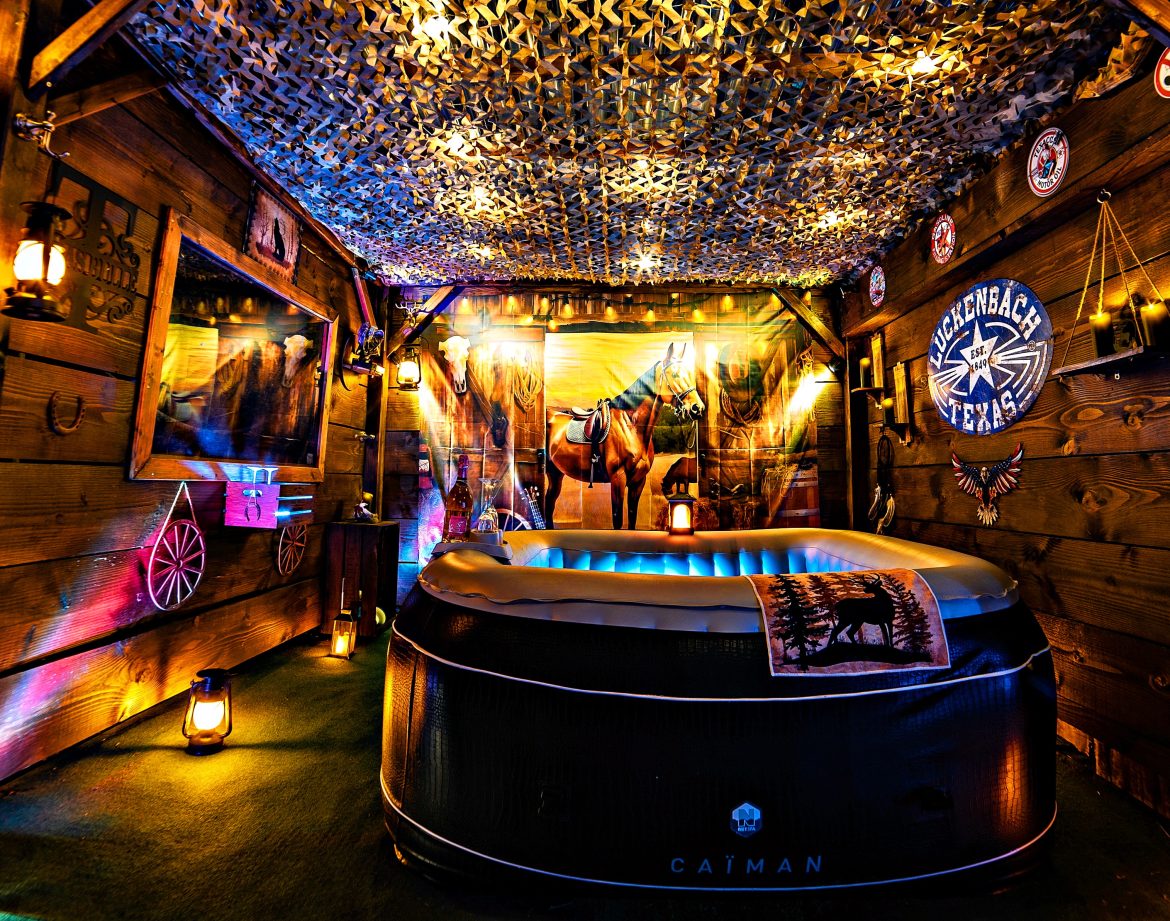 Cabane en bois avec jacuzzi, décorée de lanternes et d'éléments rustiques, ambiance chaleureuse.