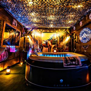 Cabane en bois avec jacuzzi, décorée de lanternes et d'éléments rustiques, ambiance chaleureuse.