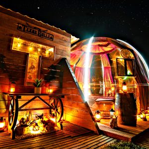 Hébergement insolite : bulle transparente illuminée, décorée de lanternes et d'éléments rustiques.