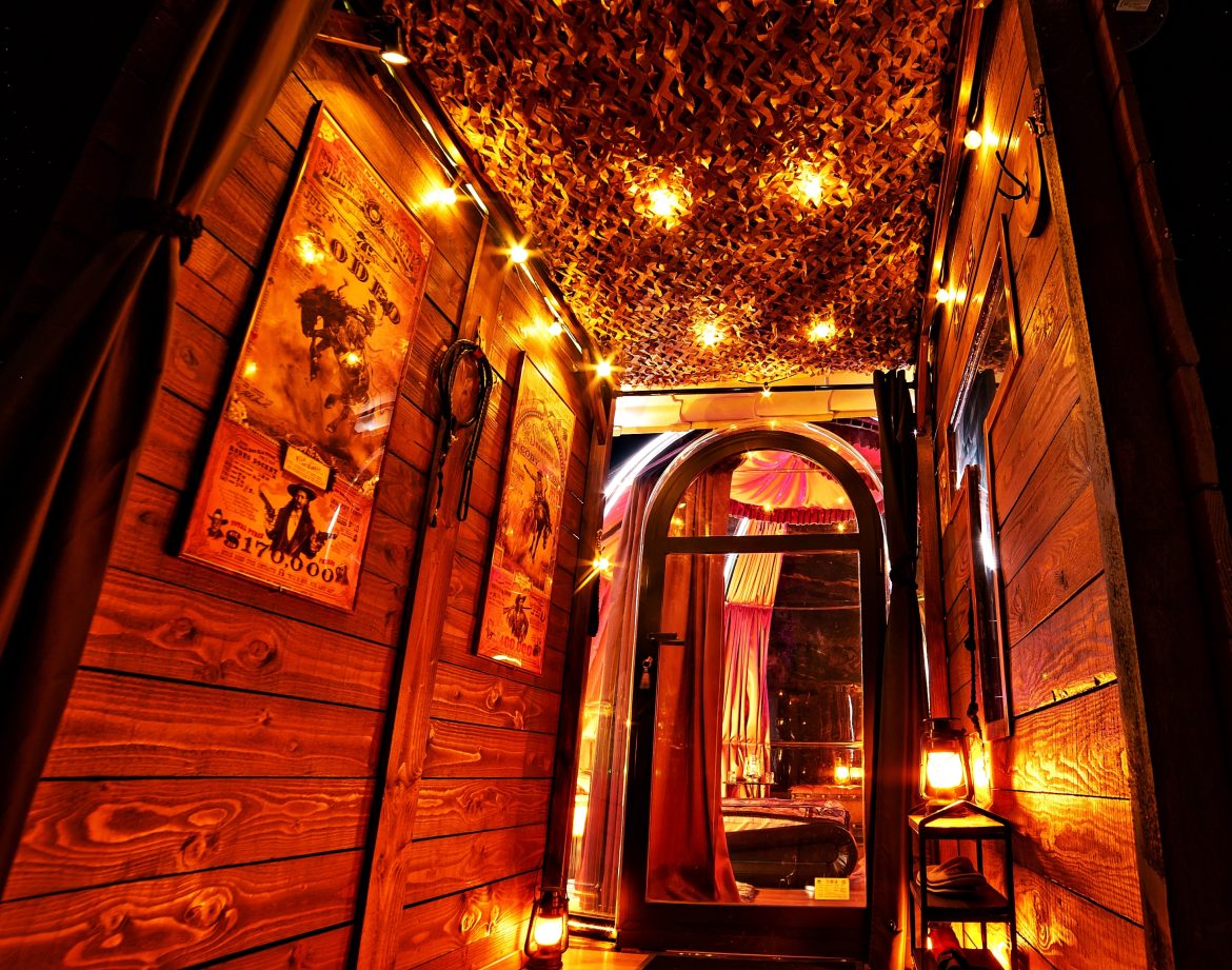 Entrée d'une cabane chaleureuse, éclairée par des guirlandes lumineuses et des lanternes.