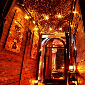 Entrée d'une cabane chaleureuse, éclairée par des guirlandes lumineuses et des lanternes.