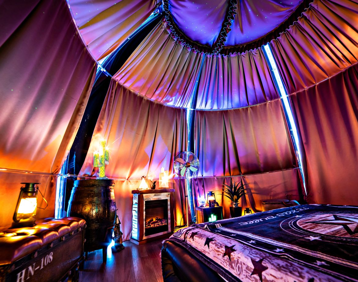 Tente luxueuse avec éclairage coloré, lit confortable et ambiance chaleureuse.