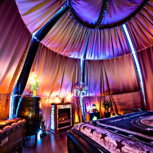 Tente luxueuse avec éclairage coloré, lit confortable et ambiance chaleureuse.