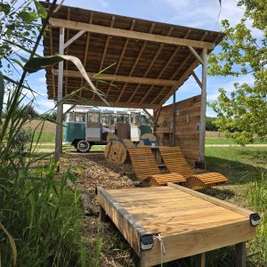 Hébergement insolite : un food truck sous un abri en bois, entouré de verdure et de calme.