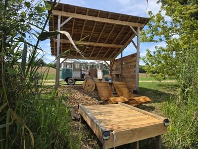 Hébergement insolite : un food truck sous un abri en bois, entouré de verdure et de calme.