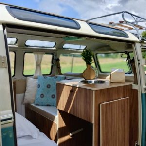 Intérieur d'un van vintage, avec un coin cuisine et des coussins colorés, idéal pour un séjour