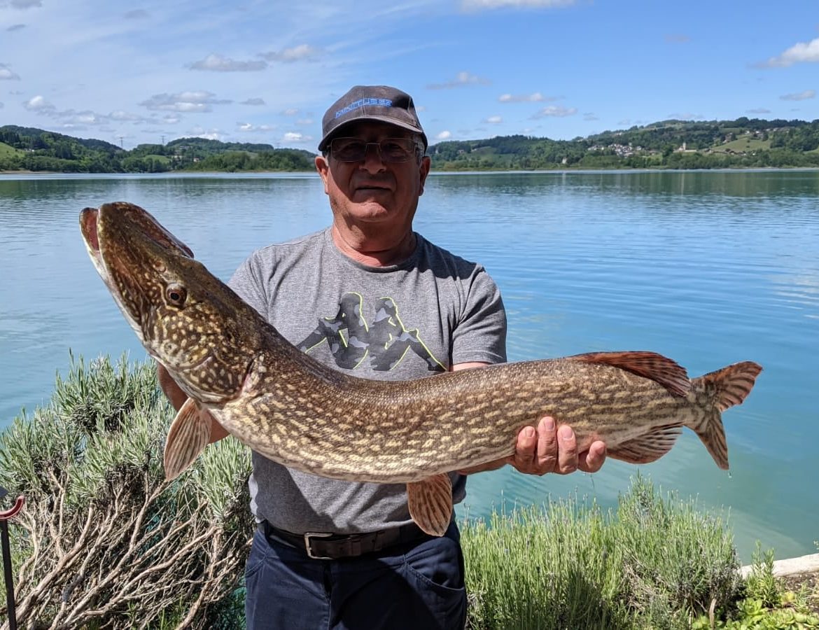 Hébergement insolite au bord de l'eau, avec un pêcheur fier de son brochet au soleil.