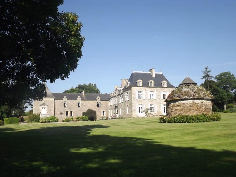 Château charmant avec un jardin verdoyant et un bâtiment en pierre pittoresque.