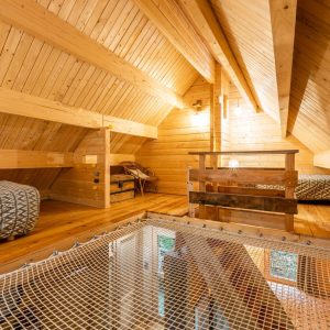 Chalet en bois avec mezzanine, lits confortables et filet suspendu pour une vue unique.