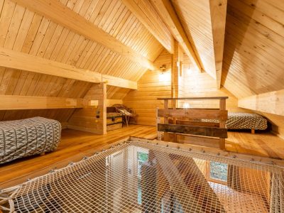 Chalet en bois avec mezzanine, lits confortables et filet suspendu pour une vue unique.