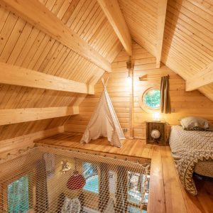 Cabane en bois avec un intérieur chaleureux, lit douillet et filet suspendu pour se détendre.