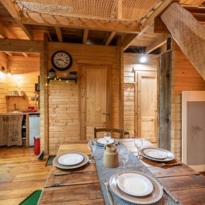 Cabane en bois chaleureuse avec un intérieur en bois, table en bois et mezzanine.