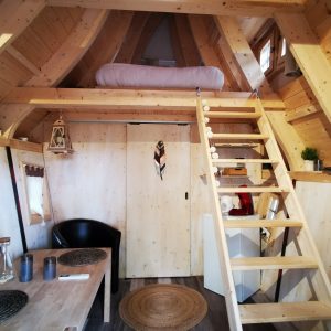 Cabane en bois cosy avec mezzanine, décorée de manière chaleureuse et lumineuse.