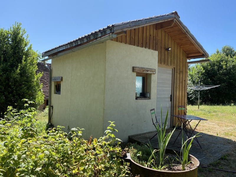 Charmante cabane en bois avec terrasse, entourée de verdure et dun jardin.