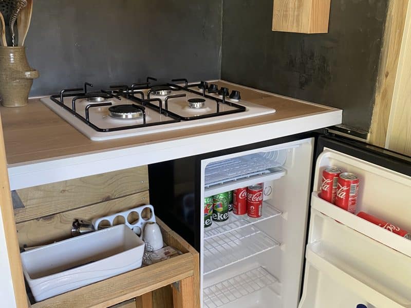Cuisine équipée dans un chalet, avec cuisinière à gaz et réfrigérateur.