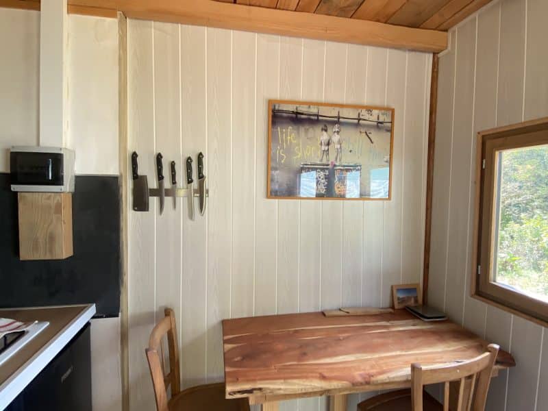 Cabane en bois avec une table en bois et des chaises, ambiance chaleureuse et rustique.