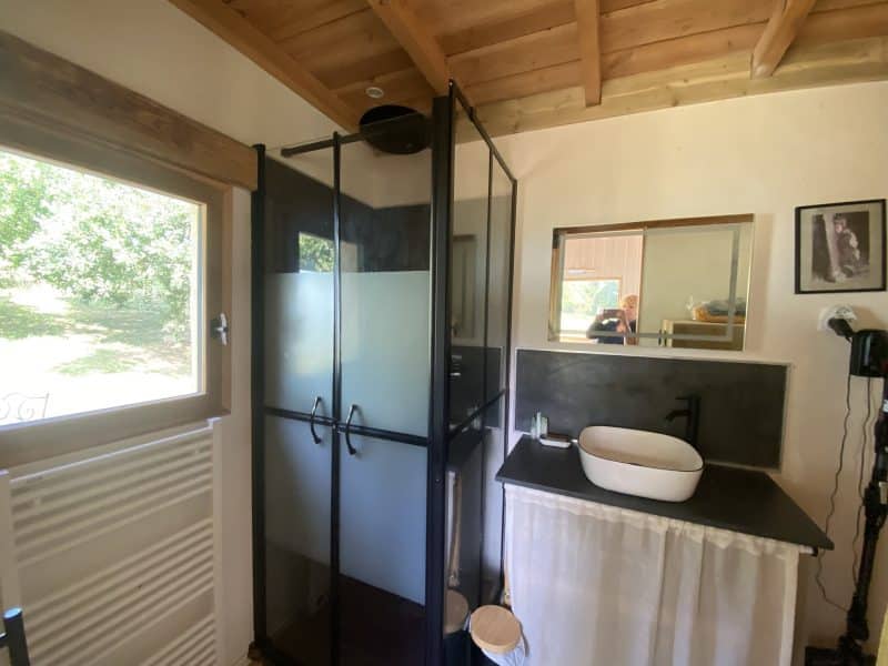 Salle de bain moderne dans un chalet, avec douche vitrée et lavabo design.