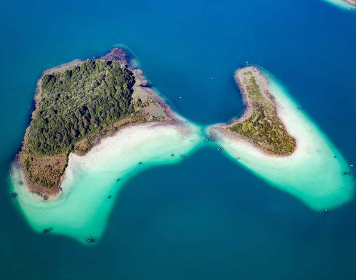 Vue aérienne de cabanes sur pilotis entourées d'eaux turquoise et de plages de sable fin.