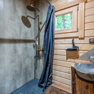Douche en bois dans un hébergement insolite, avec murs en bois et robinet doré.