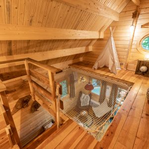 Cabane en bois avec mezzanine, parquet chaleureux et vue sur un espace de vie lumineux.