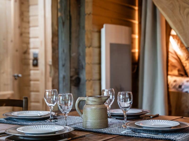 Chalet en bois chaleureux avec une table dressée pour un repas convivial.