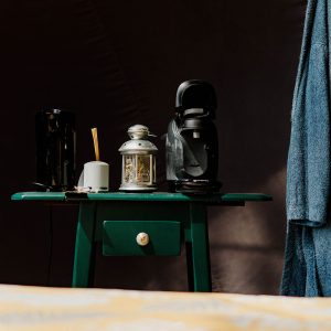 Un hébergement insolite : une table verte avec une cafetière et des peignoirs suspendus.