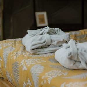 Chambre d'hôtes cosy avec draps en lin et peignoirs moelleux sur un lit douillet.