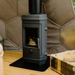 Intérieur d'une yourte avec poêle à bois, ambiance chaleureuse et cocooning.
