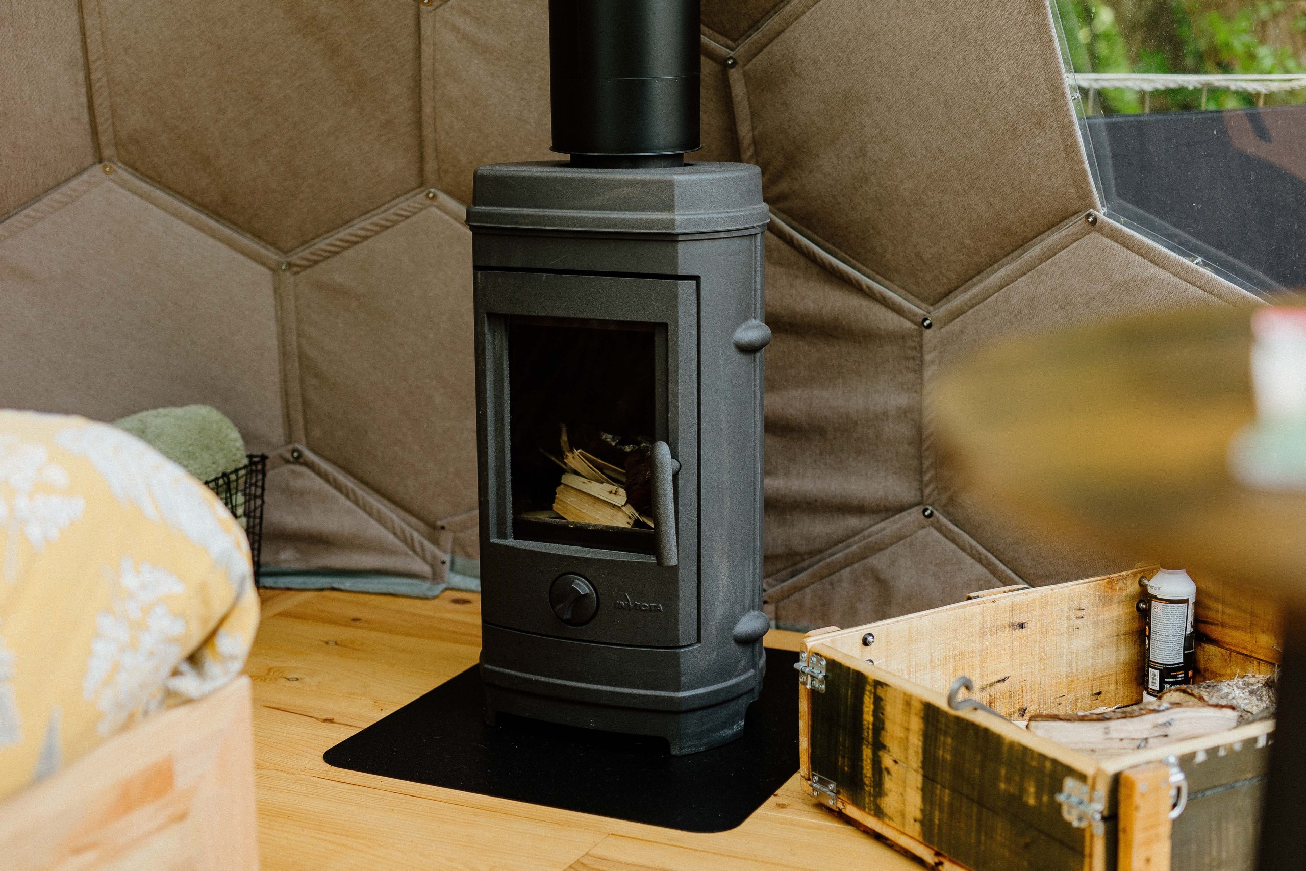 Intérieur d'une yourte avec poêle à bois, ambiance chaleureuse et cocooning.