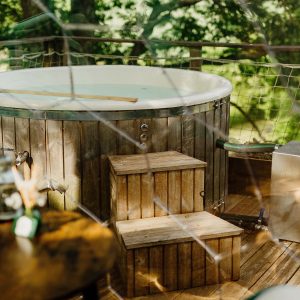 Bain nordique en bois sur une terrasse, entouré de verdure, idéal pour se détendre.