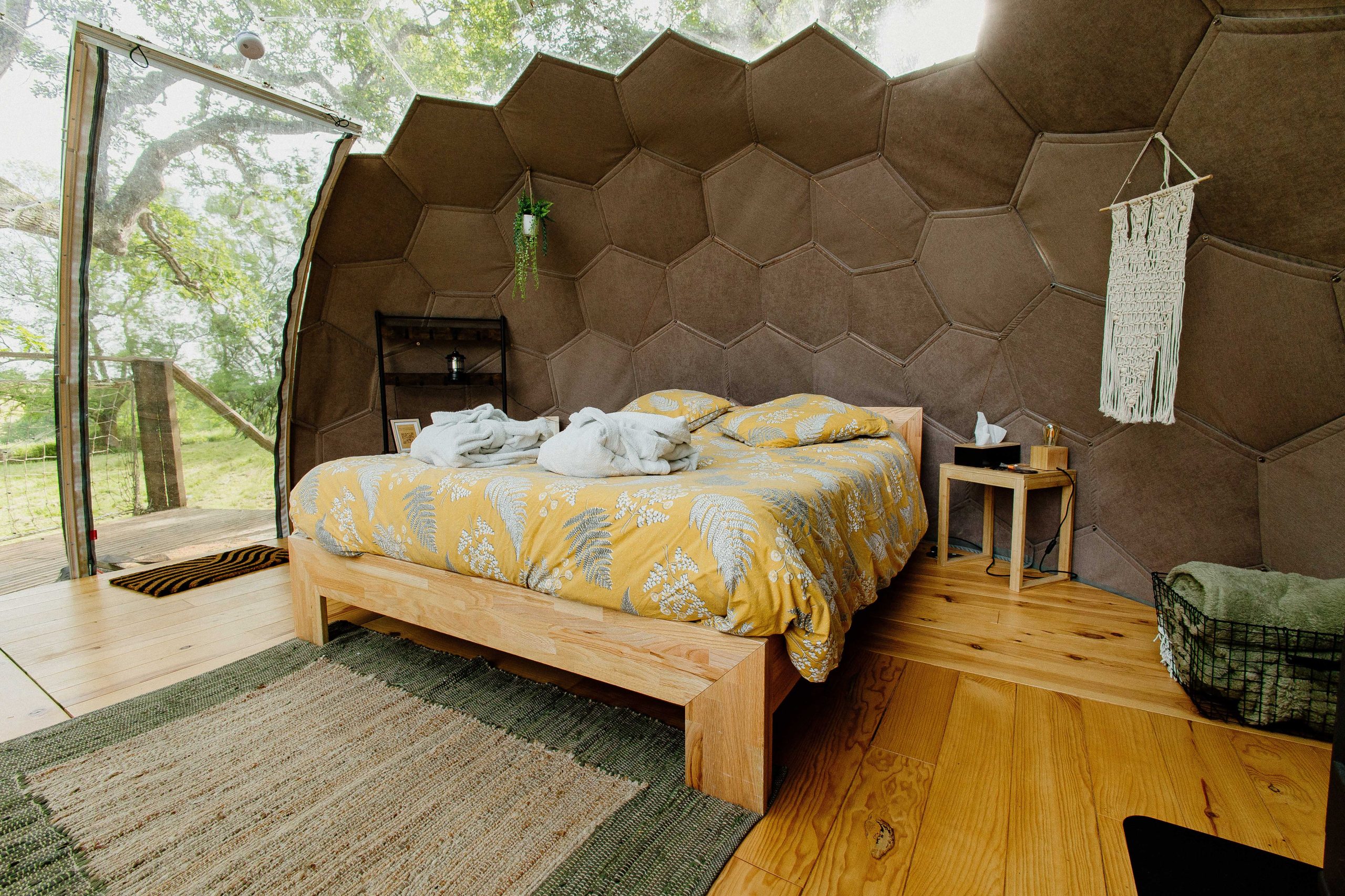 Chambre dans une cabane hexagonale, avec un lit douillet et des murs en bois naturel.