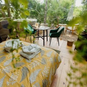 Dôme transparent avec lit douillet, coin salon et vue sur la nature environnante.