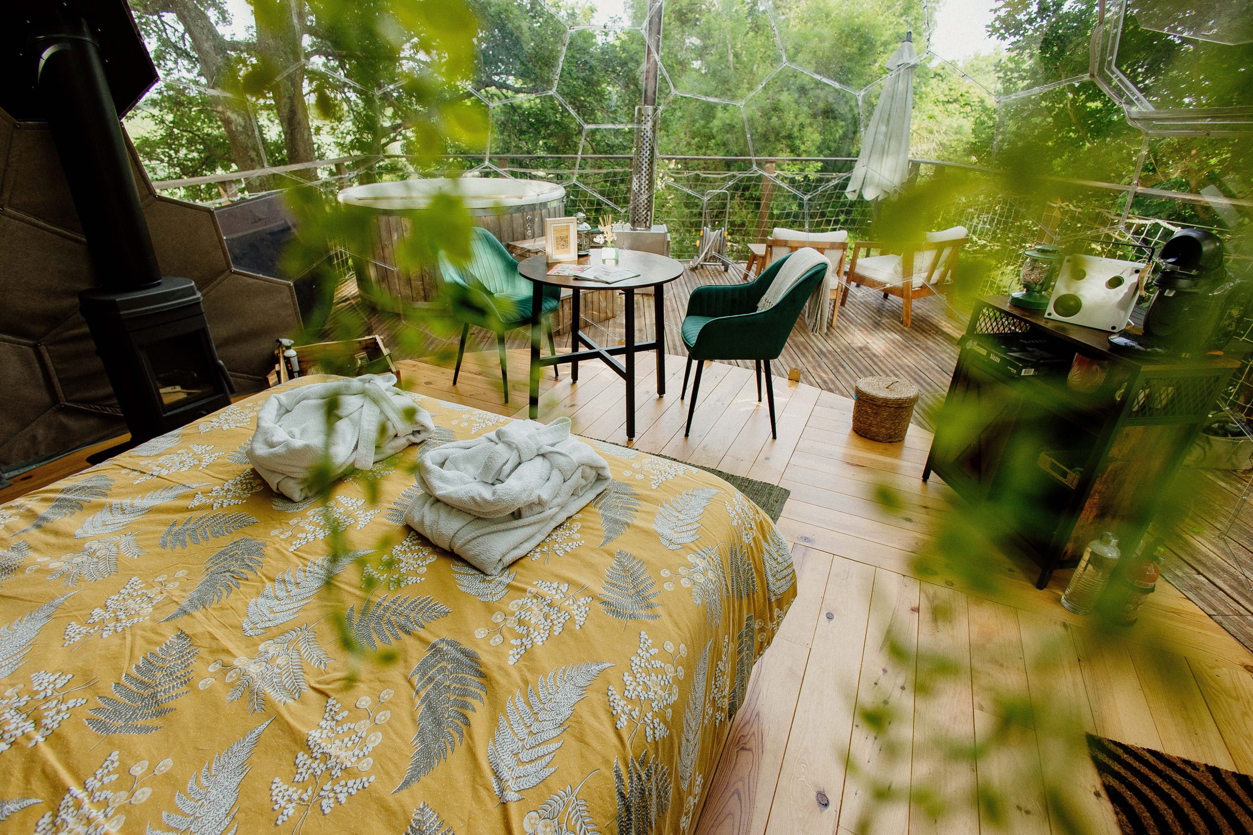 Dôme transparent avec lit douillet, coin salon et vue sur la nature environnante.