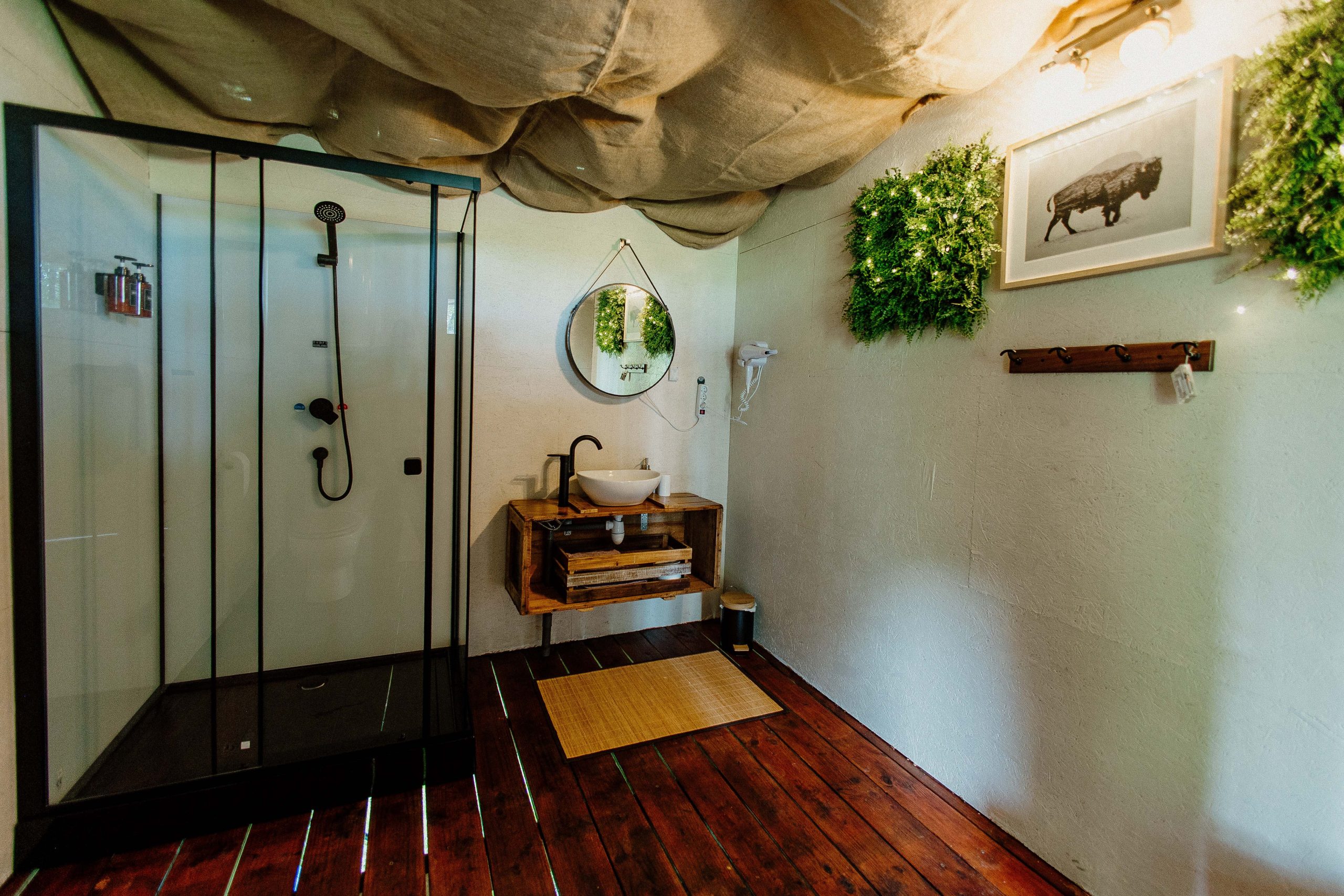 Cabane moderne avec salle de bain, décorée de plantes et bois chaleureux. Ambiance cocooning.