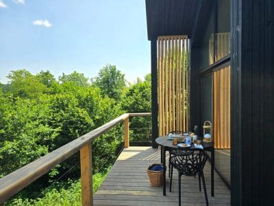 Cabane moderne en bois avec terrasse, vue sur la verdure, idéale pour un séjour relaxant.