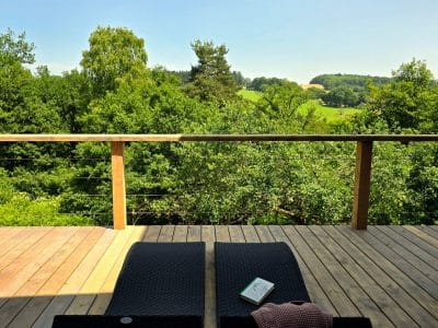 Terrasse en bois d'un chalet, vue dégagée sur la nature verdoyante et paisible.
